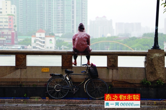 2日清晨,广州珠江新城,一男子用泡沫板遮挡风雨前行.